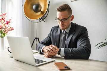 Junger Mann im Homeoffice Arbeiten am Schreibtisch Laptop konzentriert produktiv im modernen Homeoffice Umfeld