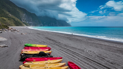 Colorful kayaks lined up on a stunning beach in Hualien, Taiwan, under a blue sky