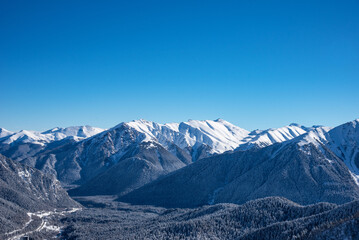 Fototapeta premium Beautiful landscape of the Arkhyz ski resort with mountains, snow, forest on sunny winter day. Caucasus Mountains, Russia.