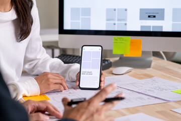 UX UI designer testing prototype on a phone, discussing and brainstorming on wireframes for a...