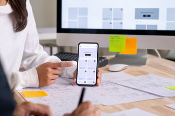 UX UI designer testing prototype on a phone, discussing and brainstorming on wireframes for a...