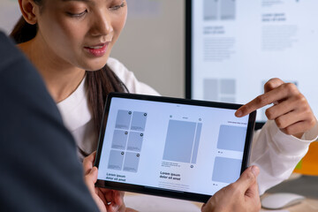 UX UI designer testing prototype on a tablet, discussing and brainstorming on wireframes for a...