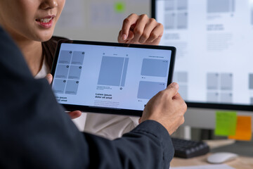 UX UI designer testing prototype on a tablet, discussing and brainstorming on wireframes for a...