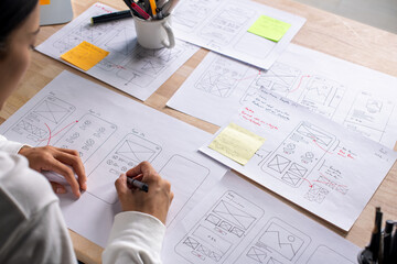 UX UI designer working on wireframes for a website and mobile app prototype, surrounded by sketches...