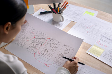 UX UI designer working on wireframes for a website and mobile app prototype, surrounded by sketches...