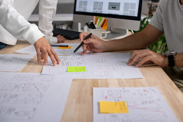 UX UI designers discussing and brainstorming on wireframes for a website and mobile app prototype, in the concept of website and mobile application design concept.