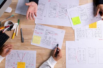 UX UI designers discussing and brainstorming on wireframes for a website and mobile app prototype,...