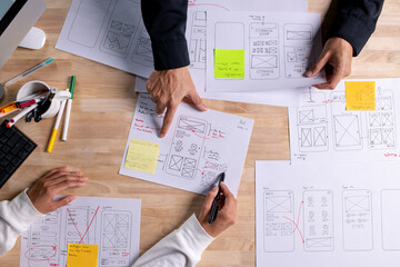 UX UI designers discussing and brainstorming on wireframes for a website and mobile app prototype,...