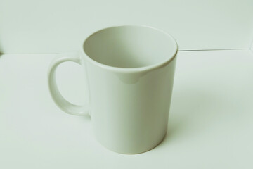Plain white mug on a white table, photo suitable for mockup example.