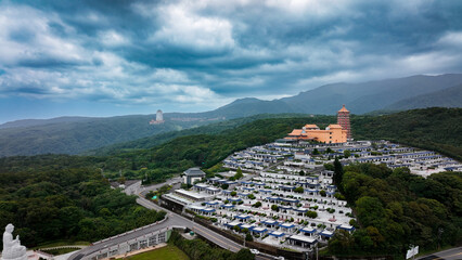 Fototapeta premium Aerial view of a serene cemetery in Taiwan surrounded by lush hills and historic buildings