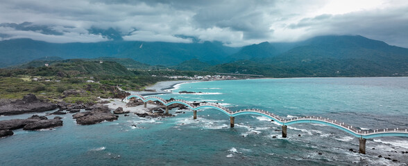 A serene view of the Sanxiantai bridge connecting land to island in Taiwan under a cloudy sky