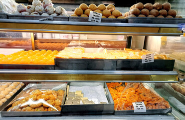 Many delicious traditional indian sweets and desserts at storefront at asian food market