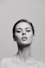 Confident woman with an elegant pose, displaying beauty and strength against a minimalistic gray background. Portrait capturing self-assurance and grace.