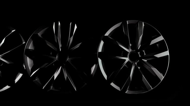New four aluminum alloy wheel disks for car without tire. Car spare parts isolated in dark background. Equipment for auto vehicle. Luxury design. Cast drive. Wide shot, truck movement