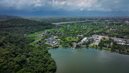 Lush green landscape of Taiwan with a river, farmland, and distant mountains under cloudy skies