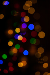 Christmas lights in the bokeh style. Red, orange, blue, yellow and green bokeh on black background, abstract bokeh style background. Concept of New Year and Christmas celebration