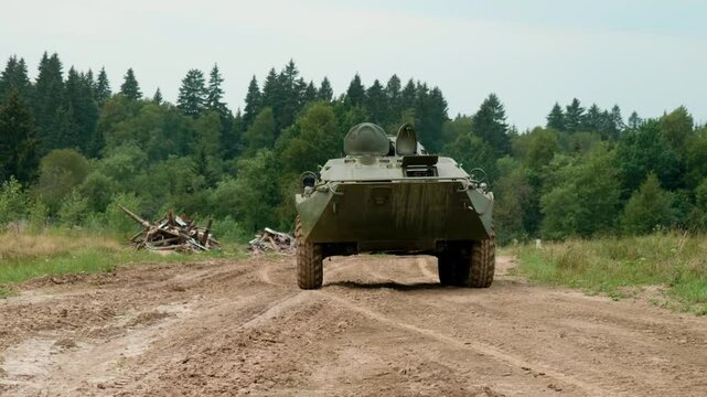 The armored personnel carrier moves across a military proving ground, demonstrating its amphibious capabilities and robust design, intended for transporting personnel and providing fire support.