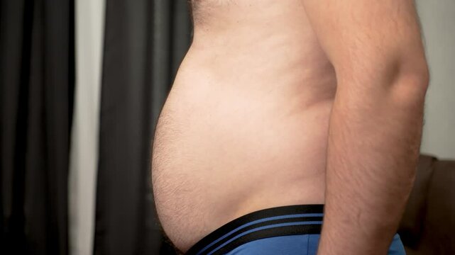 Man with early stage obesity and large sagging belly. Unrecognizable Male with obesity and protruding loose stomach. Guy with large hanging belly in initial phase of obesity
