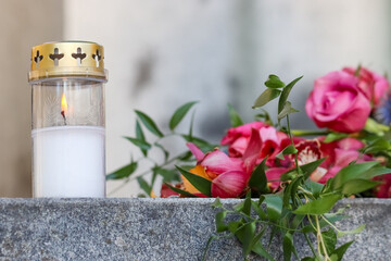 A small funeral flower arrangement. A beautiful memorial bouquet at the cemetery. The memorial flowers include red orchids. Next to the flowers is a grave candle.