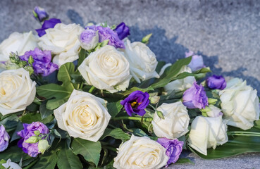 Flower arrangement. A beautiful blue and white memorial bouquet at the cemetery. Memorial flowers include white roses and blue eustoma.
