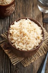 Homemade fermented cabbage or sauerkraut in a clay pot on a wooden table