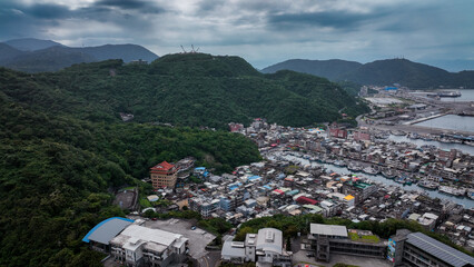 Obraz premium Aerial view of Nanfangao harbor in Taiwan with mountains and buildings on a cloudy day