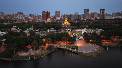 Obraz premium Aerial view of Kaohsiung city at dusk featuring illuminated parks and buildings along the river