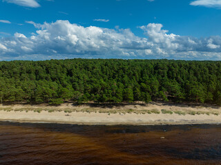 Aerial view of calm and wild Turisalu beach with a clear white sand and brown water (Estonian - Türisalu rand) on a sunny summer day. Big rocks in a calm and green Baltic sea.