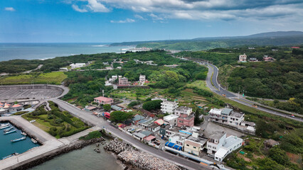 Aerial view of a coastal town in Taiwan with greenery and roads under a cloudy sky