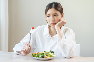 Diet in bored face, unhappy beautiful asian young woman, girl on dieting, holding fork at tomato on...