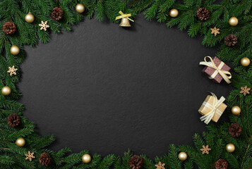 Christmas frame made of fir branches, cones and gold decorations on black background with copy space. New Year card. Top view, flat lay.