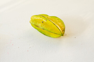 Star fruit that will soon ripen is slightly yellowish green on a white table