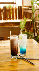 Blue squash drink and chocolate shake on wooden table with aesthetic wooden cafe background