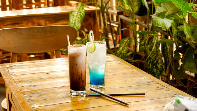 Blue squash drink and chocolate shake on wooden table with aesthetic wooden cafe background