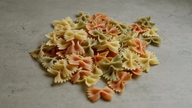 Multicolored farfalle pasta scattered on a concrete surface