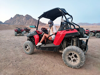 A girl is sitting in a buggy car for a desert trip. Sahara desert - active leisure and travel to Egypt.