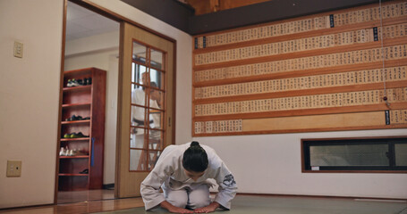 Martial arts, bow and Japanese person with respect, honor and karate etiquette in dojo. Kneeling, combat training and fight studio with sport, discipline and warrior in taekwondo class in gym © peopleimages.com