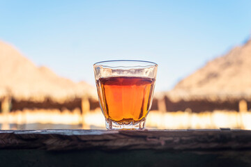 Tea in glass stands on a wooden table against the background of deserted houses. arabic tea in bedouin tent
