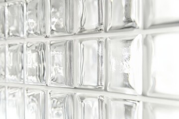 A detailed view of clear glass blocks arranged in a wall, glinting with natural light, creating an elegant and modern architectural element with transparency and texture.