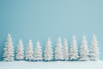 Fototapeta premium Row of snow-covered fir trees on a blue background.