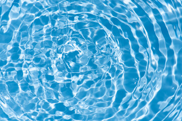 Blue water with ripples on the surface. Defocus blurred transparent blue colored clear calm water surface texture with splashes and bubbles. Water waves with shining pattern texture background.