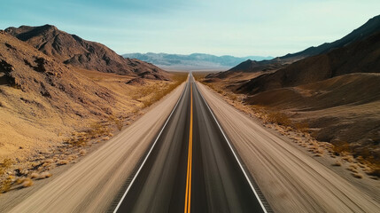 Long straight road through arid desert landscape with barren mountains under a clear blue sky