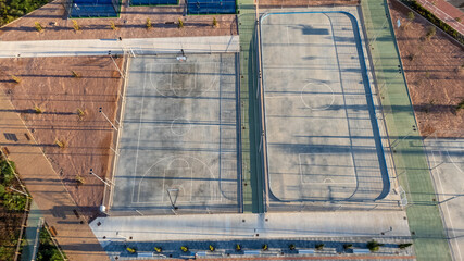 Aerial top-down view of basketball and multi-sport courts in El Chaparral, Torrevieja, featuring clean lines, pathways, and open recreational spaces