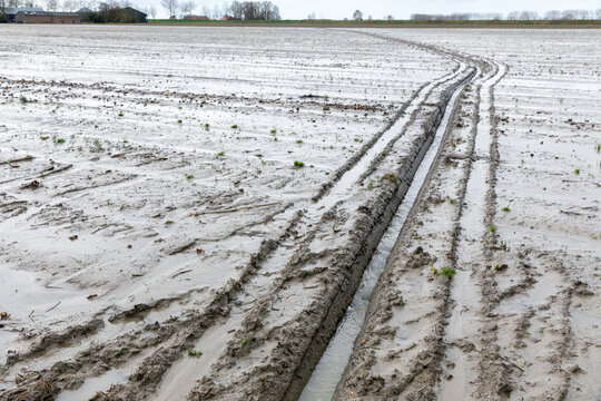 Door de vele regenval is de akker zo nat dat de boer een afwatering heeft gegraven voor de afvoer.