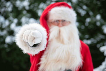 Santa Claus points finger forward in privateer with space for text for New Year and Christmas in a red fur coat Nicholas