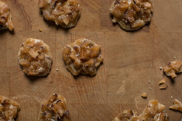 Overhead view of nigerian coconut candy on a wood countertop, top view of candied coconuts discs, flatlay of bukayo candy or coconut drops