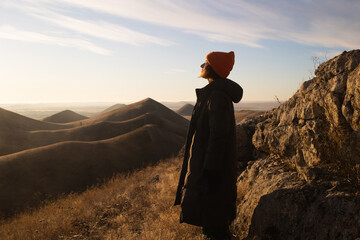 girl in warm clothes enjoying beauty of sunrise in mountains. concept of mental health, relaxation...