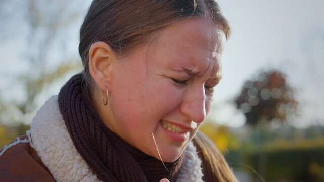 Young woman expressing various signs of pain and discomfort due to toothache. Facial expressions reveal intensity of suffering impact on her well-being. In park on bench in open air.