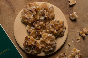 Overhead view of nigerian coconut candy on a wood countertop, top view of candied coconuts discs, flatlay of bukayo candy or coconut drops	