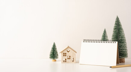 A side view minimalist Scandinavian-style desk setup with miniature trees and a blank spiral notebook, creating a cozy winter atmosphere